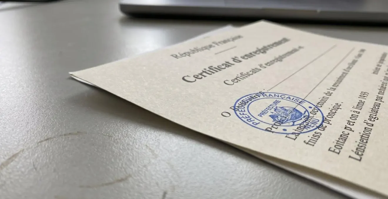 Gros plan sur un certificat d'enregistrement de navire français officiel posé sur un bureau, avec un tampon bleu de l'administration maritime partiellement visible